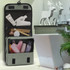 A grey toiletry bag with mesh pockets filled with various toiletry items like bottles and tubes. Features a hanging design.
