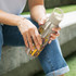 A drink bottle made of aluminium with intricate designs, featuring a beige lid and a metallic finish.