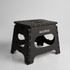 A black ASC Utility Stool with a textured surface and cut-out handles, featuring a logo on one side.
