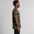 A camo-patterned T-shirt in shades of green and brown, featuring a simple design and a logo on the front.