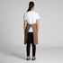 A brown canvas half apron with a tie waist, worn over a white t-shirt and black pants, featuring a back opening.