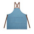 A denim apron in blue with brown leather straps and a large front pocket, featuring a logo.