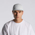 A white nylon cap with a logo, worn by a model in a plain white t-shirt.