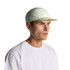 A light green nylon cap with a flat brim, featuring a logo, worn by a model in a white t-shirt.