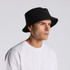 A black Terry bucket hat featured on a model wearing a white t-shirt. The hat has a logo on it.
