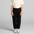 Black youth track pants displayed on a child, paired with a light-coloured t-shirt and casual shoes. It features an elastic waistband.