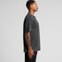 A man stands in profile wearing a dark stone wash heavy T-shirt. The shirt has a relaxed fit and visible texture.