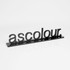A black promotional display with the word "ascolour" in stylish lettering, reflecting on a smooth surface.
