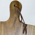 A wooden recipe book holder with a hanging loop, featuring a natural brown finish and a leather tie.