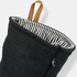 A dark grey oven mitt with a striped interior and a leather loop for hanging. It features a small logo.