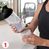 A drink bottle with a black lid and clear body, held alongside a small storage cup.