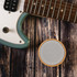 A Bluetooth speaker featuring a bamboo exterior, positioned beside an electric guitar on a wooden surface.