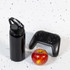 A drink bottle in black with a flip straw lid, accompanied by a red apple and a black gaming controller.