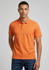 An orange polo shirt with a collared neckline, featuring a logo, worn by a model against a neutral background.