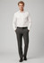A man stands wearing a white shirt and grey classic flat pants, paired with a belt and black shoes. The outfit includes branding.