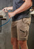 Men's rugged cargo shorts in light brown, featuring multiple pockets and a logo, displayed on a model.