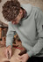 A unisex multi-pocket hoodie in green worn by a person working on wood, featuring a logo on the sleeve.
