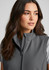 A women's grey vest with a high collar and a zip front, featuring a sleek design and a logo.