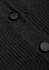 A close-up of a black cardigan featuring textured fabric and two round buttons.