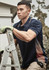 A dark navy short sleeve polo featuring a patterned side detail, worn by a man on a ladder.