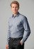 A long sleeve button-up shirt in light blue with a pocket, featuring a logo. Model is wearing black trousers.