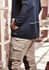 A navy unisex waterproof jacket is worn by a person with their hand in their pocket, paired with beige cargo pants.