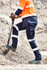Mens essential stretch cargo pant in navy, featuring reflective stripes, worn with work boots and an orange high-visibility shirt.