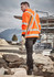 A unisex hi vis orange jumper with reflective X-back stripes, set against a construction site backdrop.