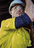 A man wearing a bright yellow long sleeve work shirt with navy blue accents, accompanied by safety glasses and a hard hat.