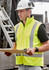 A man wearing a bright yellow waterproof reversible vest with reflective stripes, holding a clipboard.
