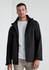 A man wearing a black rain jacket with a hood, featuring a zip-up front and a logo.