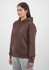 A brown hoodie with a front pocket and drawstrings, featuring a logo. Model wearing it with grey pants.
