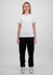 A woman in a white t-shirt and black track pants stands against a plain background. The pants have a branding logo.