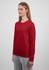 A long sleeve women's tee in red, featuring a simple design and a snug fit. The model is wearing grey pants.