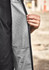 A unisex softshell jacket in black and grey, featuring a textured interior and a hand holding the inner layer.