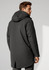 A man in a black unisex rain jacket with a hood, featuring a simple design and a slight split at the back.
