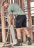 Men's streetwear comfort shorts in black, paired with a green shirt, worn by a man working on a construction site.