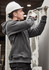 A grey unisex zip front multi-pocket hoodie worn by a worker using a tool, with a safety helmet and gloves.
