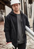 A black unisex zip front multi-pocket hoodie displayed on a person wearing gloves and a hard hat in a work environment.
