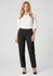 A woman wears black slacks paired with a white button-up shirt and heels, posing against a neutral background.