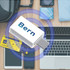A Type-C to Type-C data blocker in white, surrounded by a laptop, phone, travel tickets, and a blue tie.