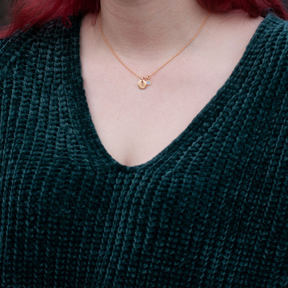 Model wearing Custom Hand Stamped Gold initial birthstone necklace, personalized with child's initial & blue birthstone