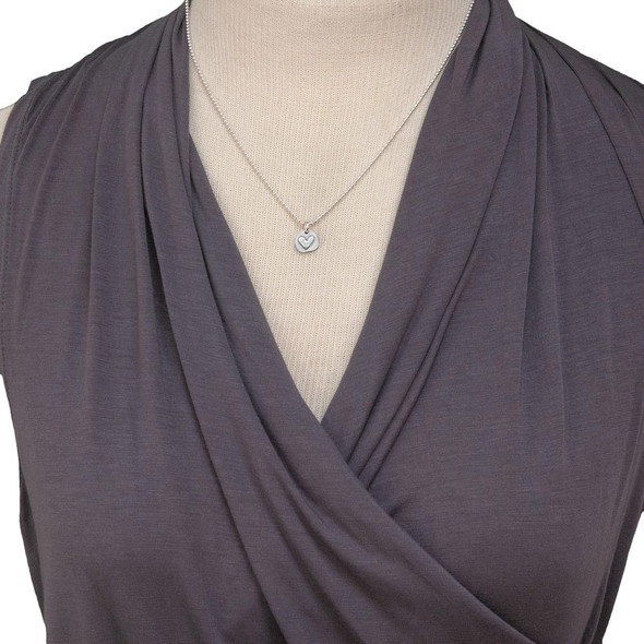 Handmade silver heart charm with stamping on back, shown on model