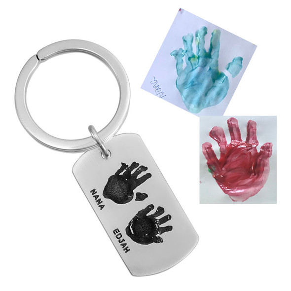 Custom silver key ring gift for Dad with kids actual handprint engraved on the front, with their names stamped below, shown with the original painted handprints used to personalize they key chain