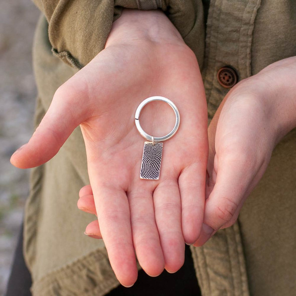 Model holding custom silver memorial key ring personalized with loved one's fingerprint