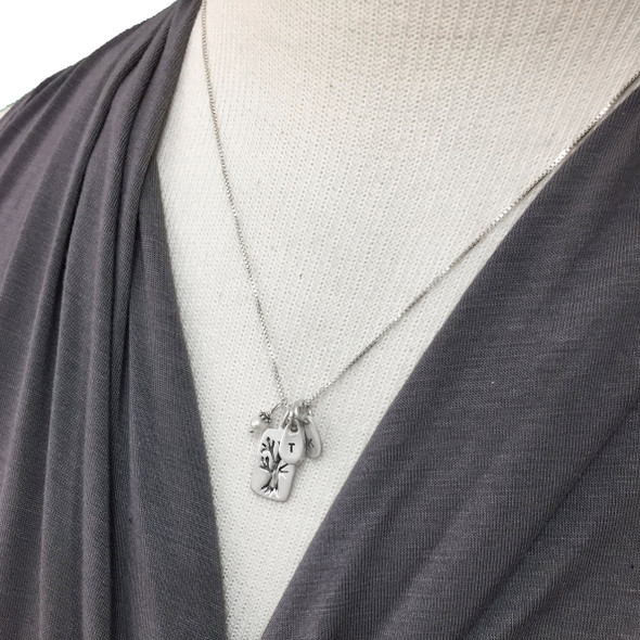 Model wearing custom fine silver Family Tree necklace, personalized with hand stamped kids' initials, hung with pearl charm