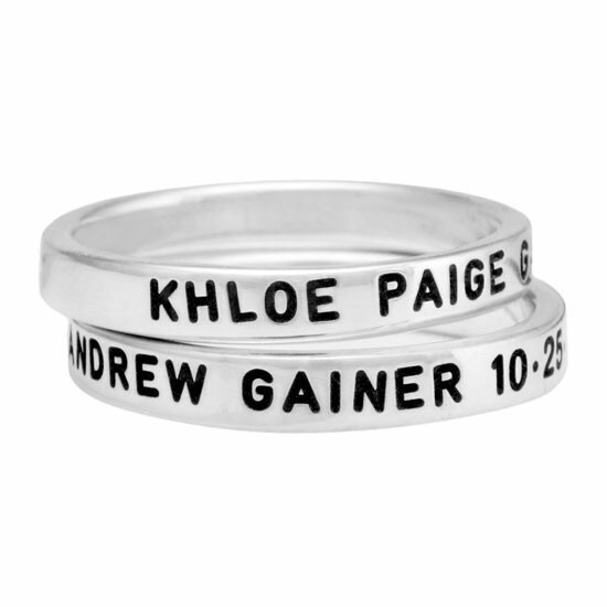 Hand stamped sterling silver stackable rings, personalized with kids names and birth dates, shown close up on white