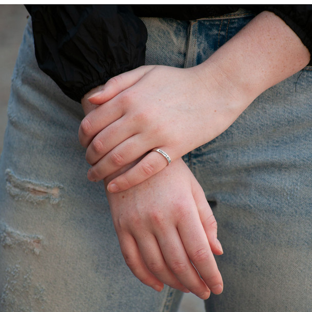Model wearing hand stamped sterling silver stackable ring, personalized with kid's name