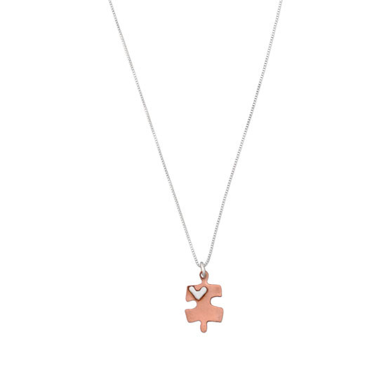 Handmade copper puzzle piece charm with silver heart on a necklace, shown on white
