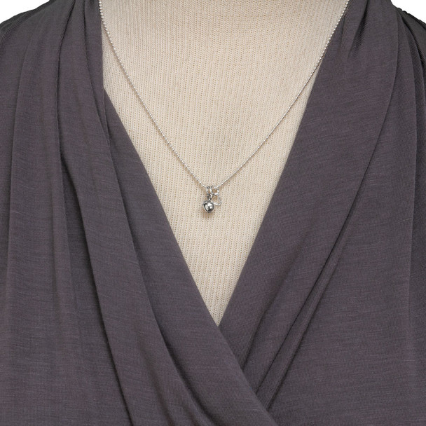 Tiny sterling silver apple charm for teachers, side shown on necklace on a model